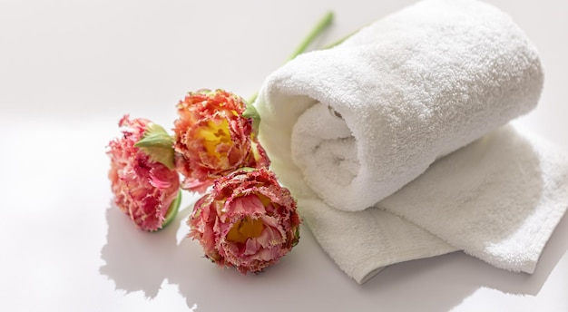 Foto gratuita flores y toallas de baño de felpa blanca de primer plano