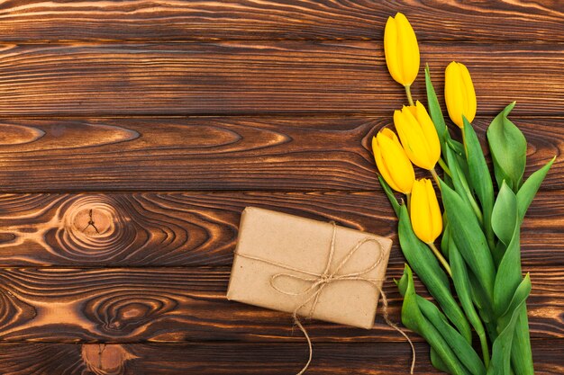 Flores de tulipán amarillo con regalo en mesa