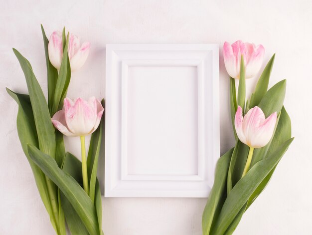 Flores de tulipán con marco en blanco sobre mesa