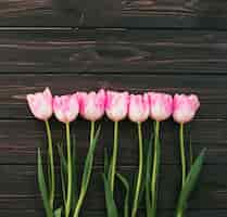 Foto gratuita flores de tulipán rosa esparcidas en mesa de madera