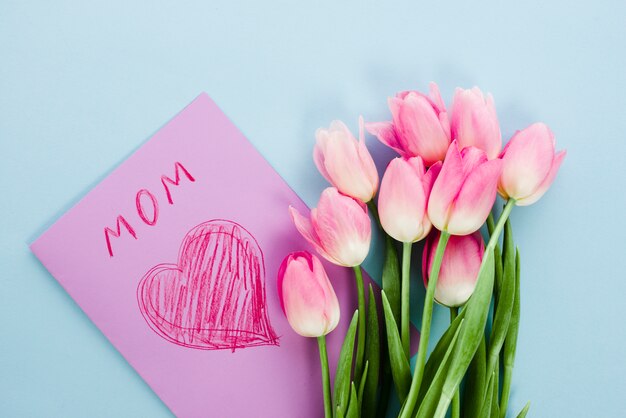 Flores de tulipán con tarjeta de felicitación con inscripción de mamá.