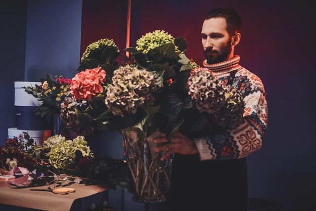 El florista barbudo experimentado acaba de crear un hermoso ramo grande y listo para ponerlo en la sala de exposición.