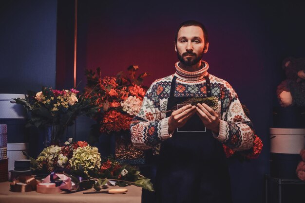 El florista barbudo experimentado está creando un bonito ramo usando una variedad de flores.