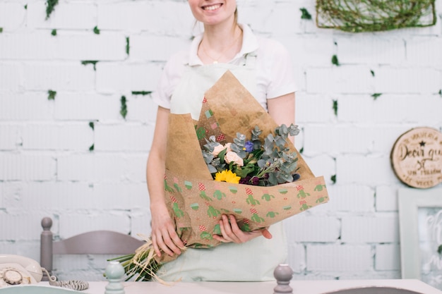 Florista de cultivos que muestra un ramo envuelto