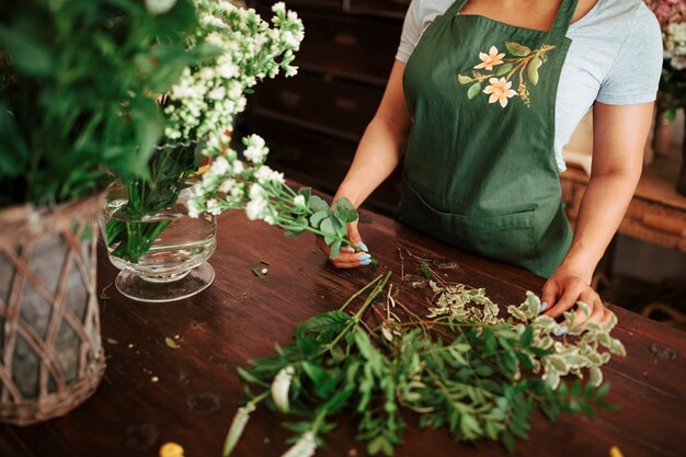 Florista de sexo femenino que sostiene el manojo de flores blancas frescas sobre el escritorio de madera