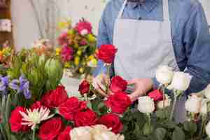 Foto gratuita un florista de sexo masculino que arregla las rosas frescas en la floristería.