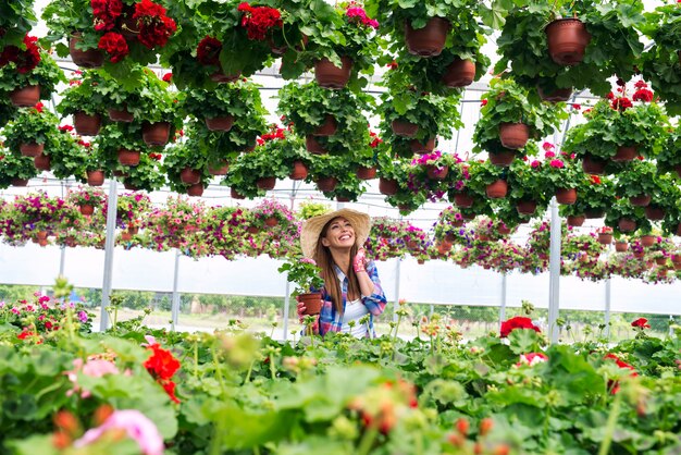 Floristería encantadora mujer cuidando de flores en invernadero y disfrutando de su trabajo