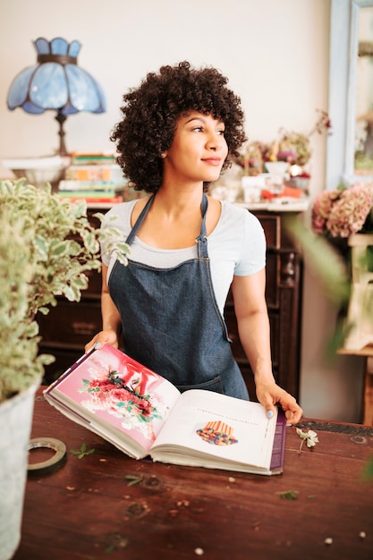 Foto gratuita floristería femenina africana con álbum de fotos de flores en la tienda