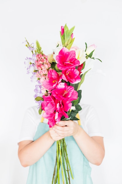 Floristería femenina escondiendo su rostro detrás de ramo de flores