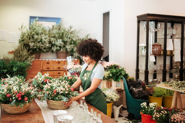 Floristería femenina que arregla la cesta de flores en tienda floral