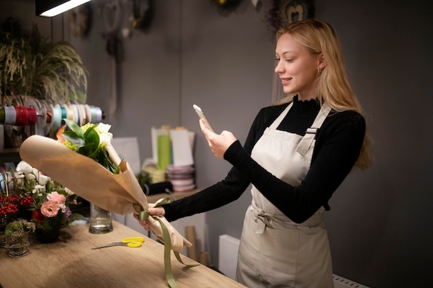 Floristería femenina tomando una foto de un ramo recién hecho