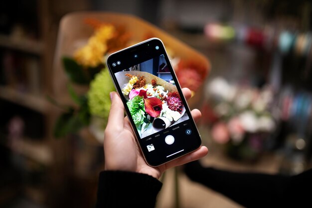 Floristería femenina tomando una foto de un ramo recién hecho