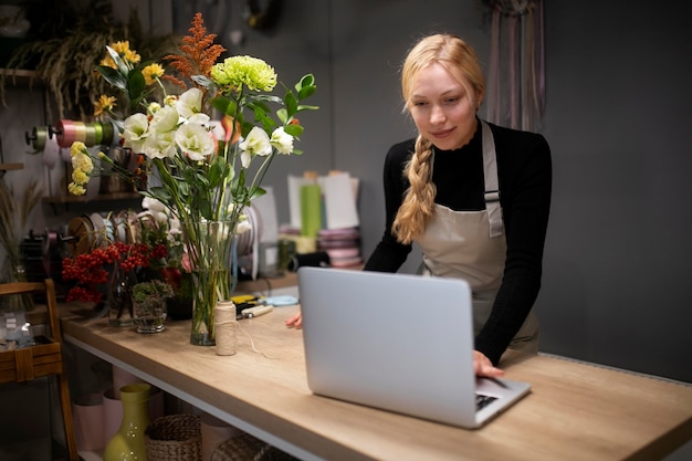 Floristería femenina usando una computadora portátil en el trabajo