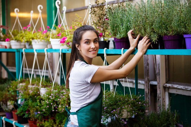 Floristería hermosa joven que cuida las flores.