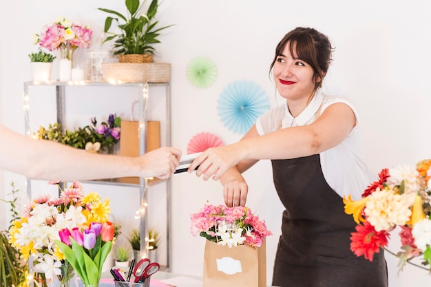 Floristería mujer aceptando tarjeta de crédito de su cliente.