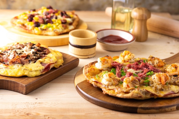 Foco suave de pizzas caseras tradicionales con diferentes ingredientes en una mesa de madera