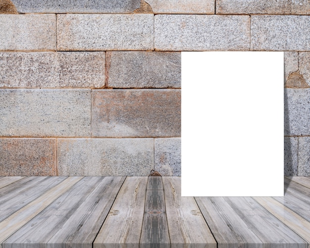 Folio en blanco sobre una mesa de madera y apoyado en una pared