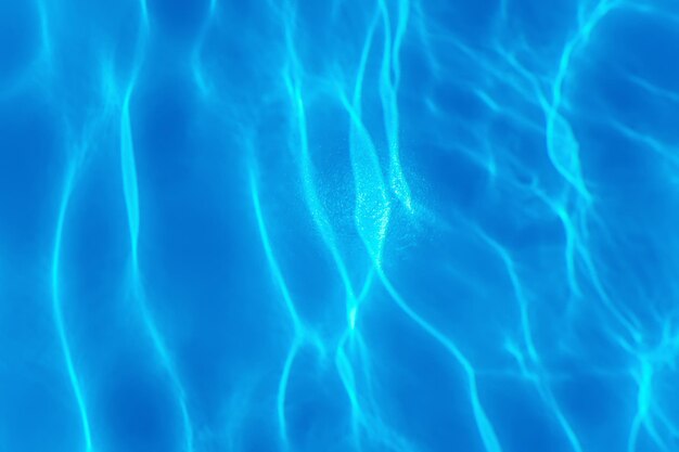 Fondo de agua ondulada azul, reflejo del sol en el agua de la piscina