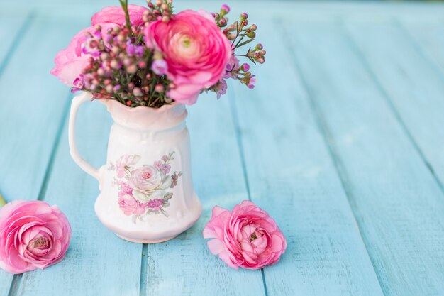 Fondo azul con flores rosas y jarrón decorativo