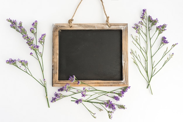 Fondo blanco con pizarra y flores moradas