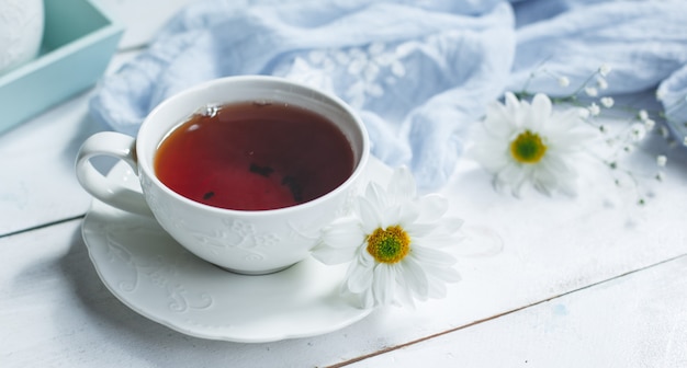 Fondo blanco, taza de té y margaritas.