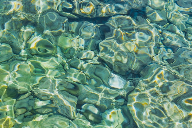 Fondo borroso de agua clara transparente en la bahía del mar Egeo brilla en la idea del sol para un fondo o postal