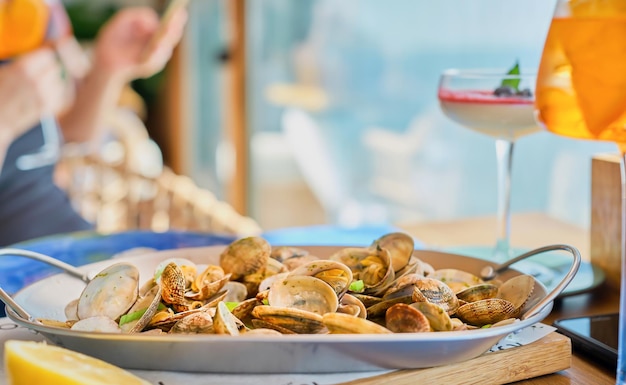 Fondo borroso con un plato de almejas vongole hervidas en una mesa en un café con espacio de copia Idea para pantalla de inicio o pancarta