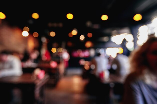 Fondo borroso de restaurante o cafetería. Mesas y sillas en el vestíbulo del centro comercial. Visitantes al restaurante para la cena. Hermoso interior luminoso. Fondo básico bokeh borroso para el diseño