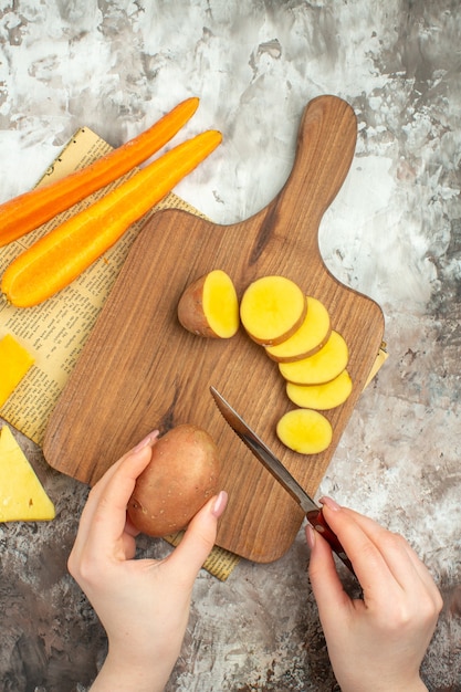 Fondo de cocina con varias verduras y dos tipos de cuchillo de queso en la tabla de cortar de madera