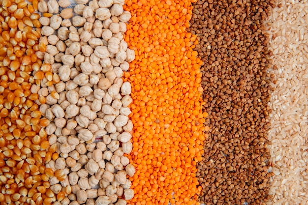 Fondo de diferentes tipos de granos de maíz, garbanzos, lentejas rojas, trigo sarraceno y arroz vista superior