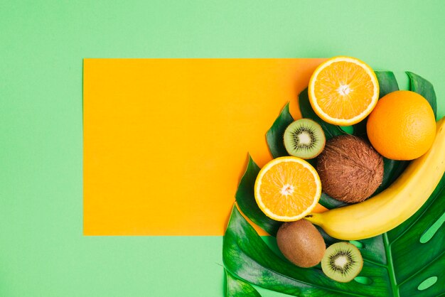 Fondo de frutas tropicales con plantilla de tarjeta y hoja de palmera