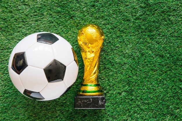 Fondo de fútbol en césped con pelota y trofeo