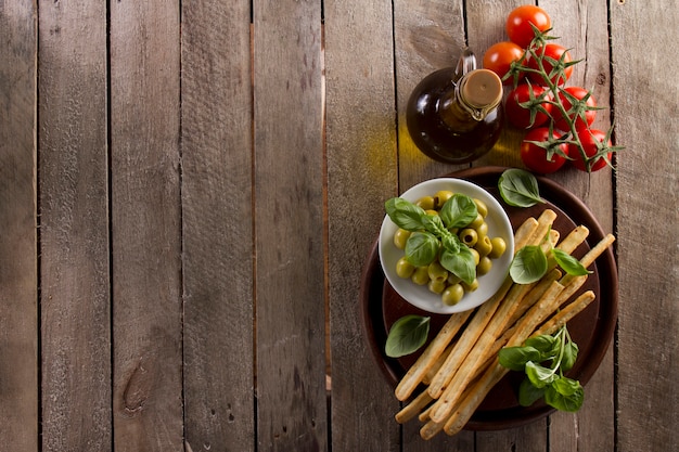 Fondo de madera con aceite de oliva, tomates y aceitunas