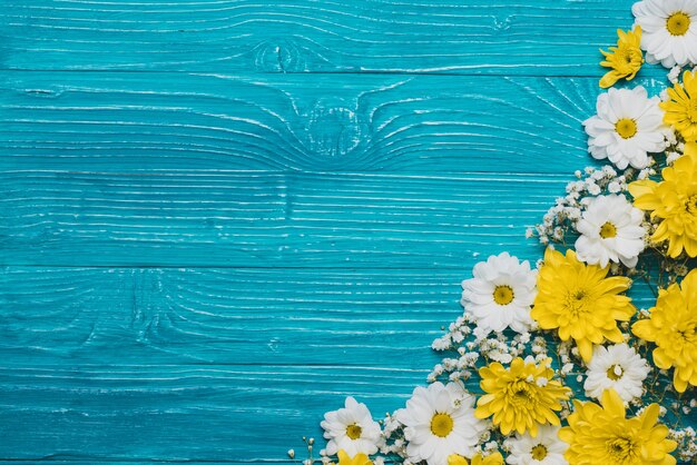 Fondo de madera azul con flores blancas y amarillas