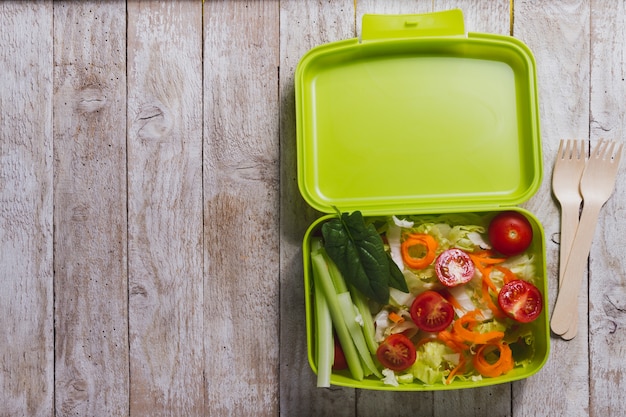 Fondo de madera con ensalada y cubiertos