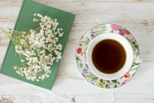 Foto gratuita fondo de madera con taza de café, flores y libro