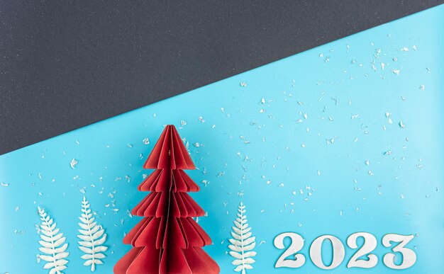 Fondo de navidad con árbol de papel de origami y número 2023 plano