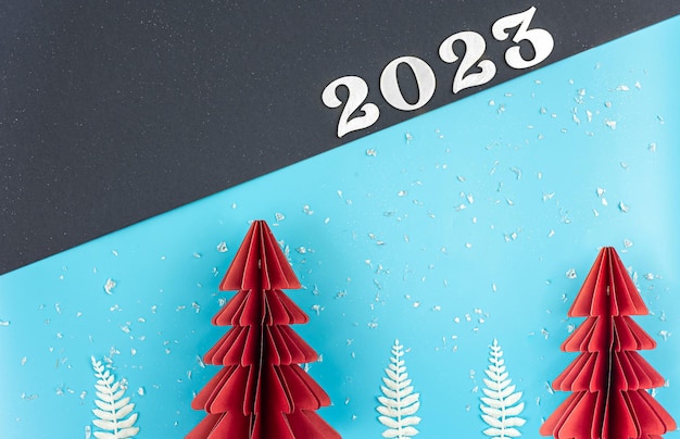 Fondo de navidad con árbol de papel de origami y número 2023 plano