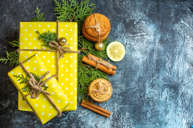 Fondo de Navidad con hermosas cajas de regalo amarillas y galletas apiladas limón canela limas en el lado derecho sobre fondo oscuro