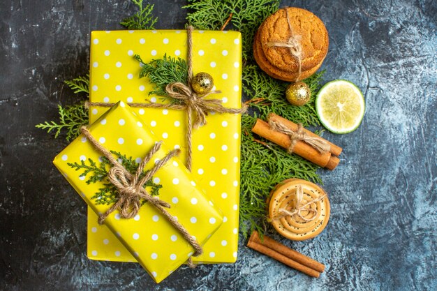 Fondo de Navidad con hermosas cajas de regalo amarillas y galletas apiladas limón canela limas sobre fondo negro