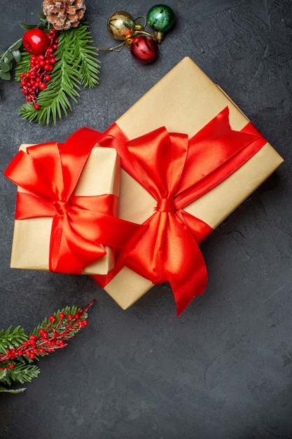 Fondo de Navidad con hermosos regalos con cinta en forma de arco y accesorios de decoración de ramas de abeto en una mesa oscura vista vertical
