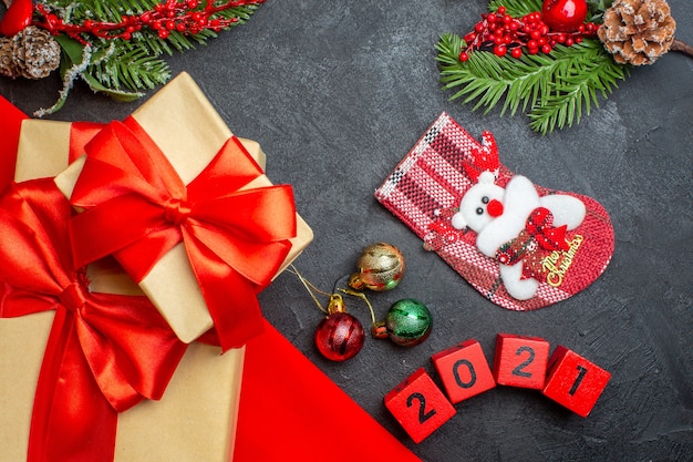 Fondo de Navidad con hermosos regalos con cinta en forma de arco sobre una toalla roja y accesorios de decoración de calcetines de Navidad de números en una mesa oscura