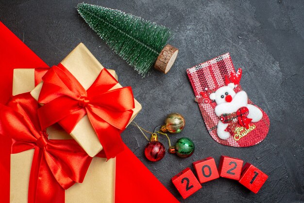 Fondo de Navidad con hermosos regalos con cinta en forma de arco sobre una toalla roja y accesorios de decoración de calcetines de Navidad de números en una mesa oscura