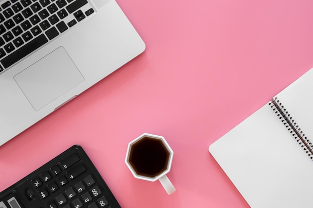 Fondo de oficina con computadora portátil de café sobre fondo rosa