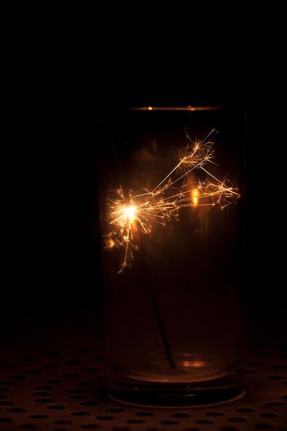 Foto gratuita fondo oscuro con vaso y bengala