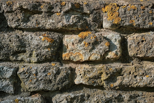 Fondo de piedra Una casa antigua hecha de piedra áspera sin tratar cubierta de musgo Idea para la fachada de una casa o diseño de edificios y espacio interior