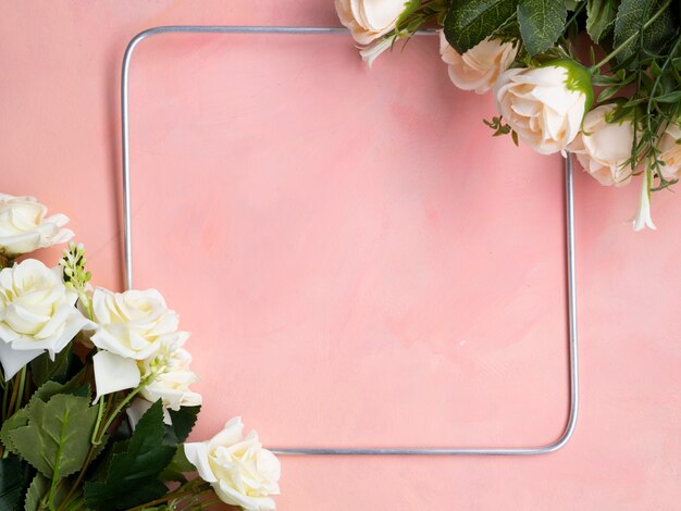 Fondo plano de color rosa con marco de rosas blancas