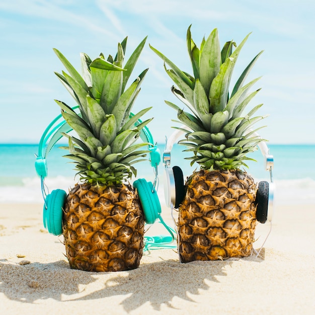 Foto gratuita fondo de playa con dos piñas con auriculares