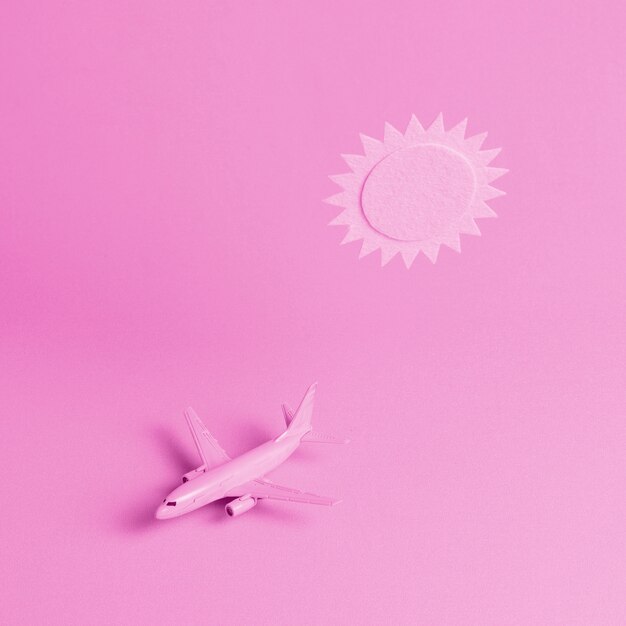 Fondo rosa con avión y sol