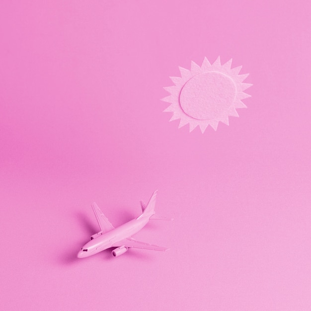 Fondo rosa con avión y sol